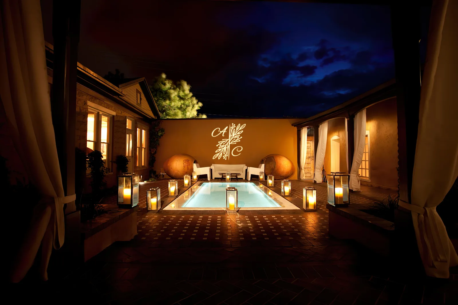 Courtyard monogram over a pool after dark — Dark setting