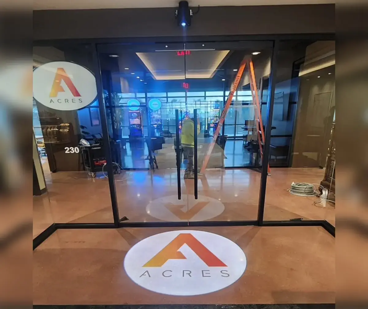 ACRES triangle logo projected on the glass entrance floor of a corporate office