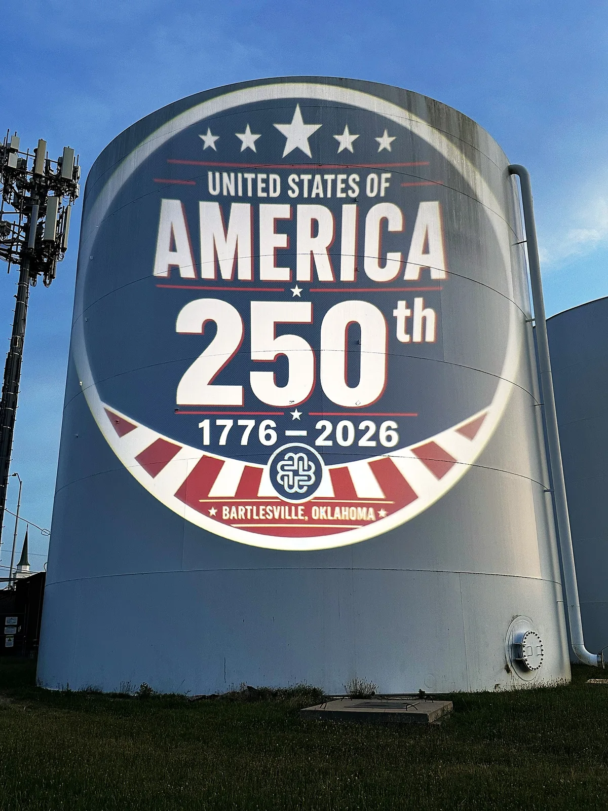 The United States 250th anniversary seal projected across a municipal water tower at dusk