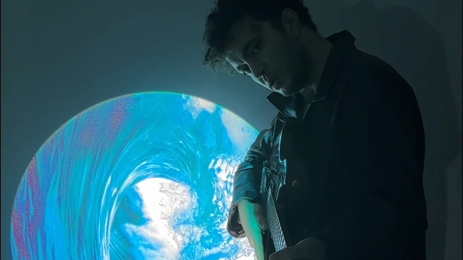 Live performer lit by a projected neon-toned gobo effect on stage