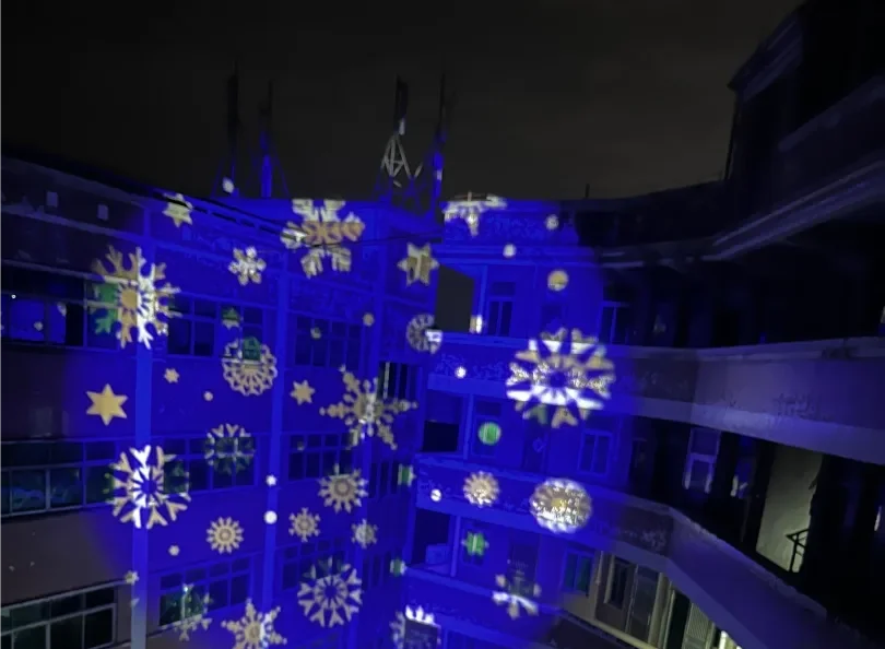 Blue and gold snowflake patterns projected across an apartment courtyard