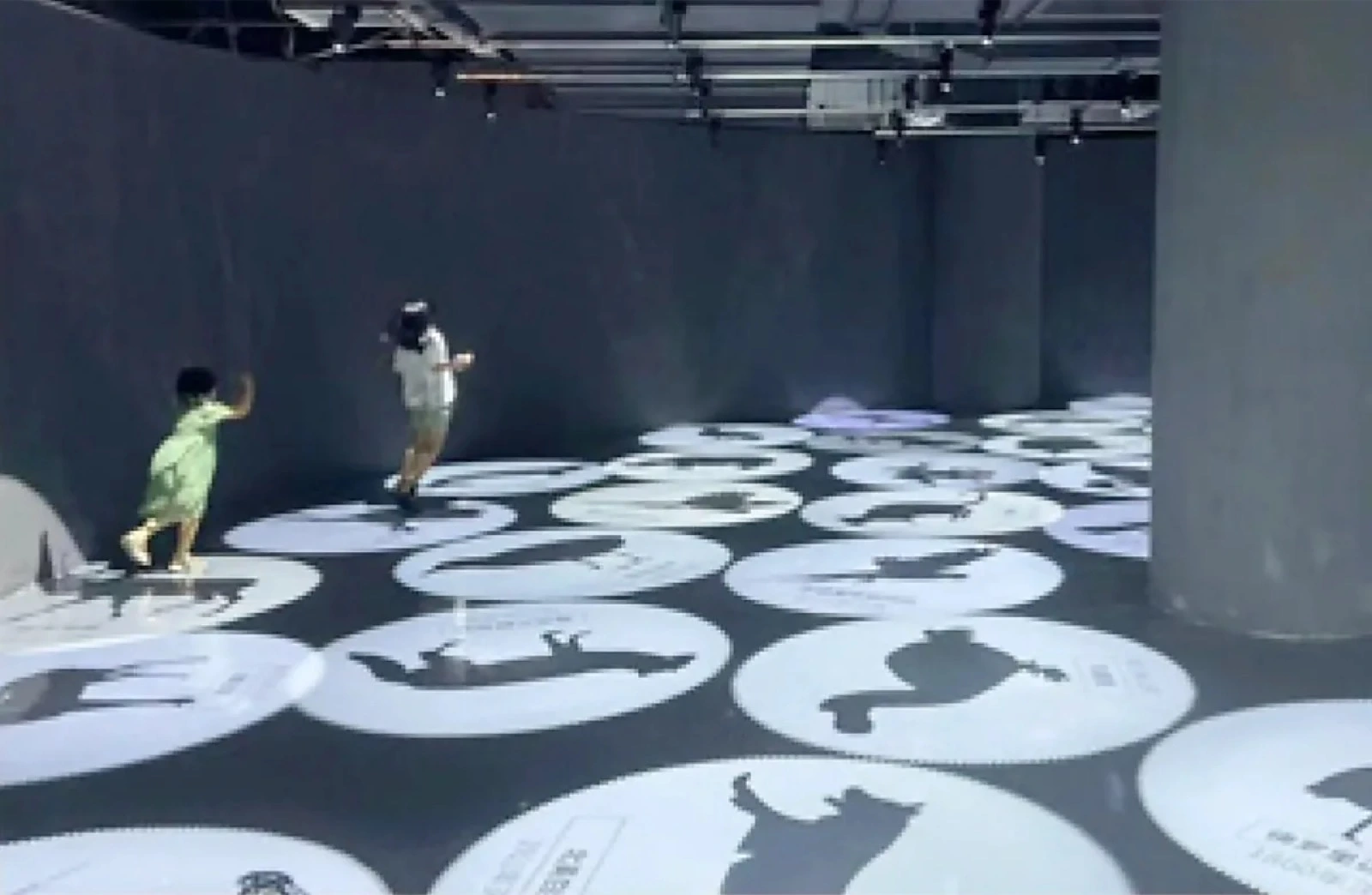 Kids playing an animal-silhouette floor game projected in a museum