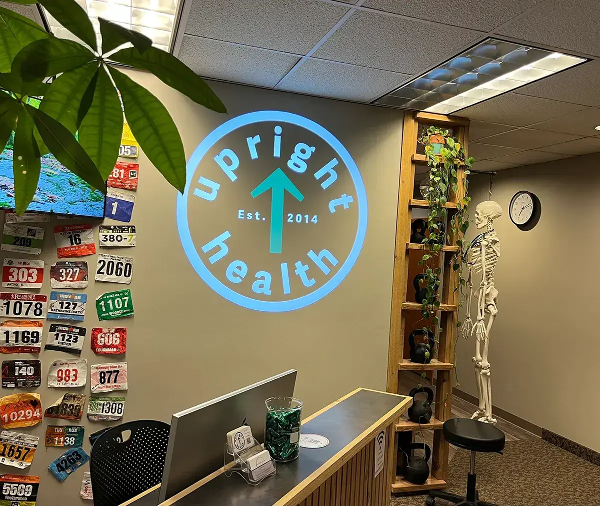 Upright Health arrow logo projected above a clinic reception desk