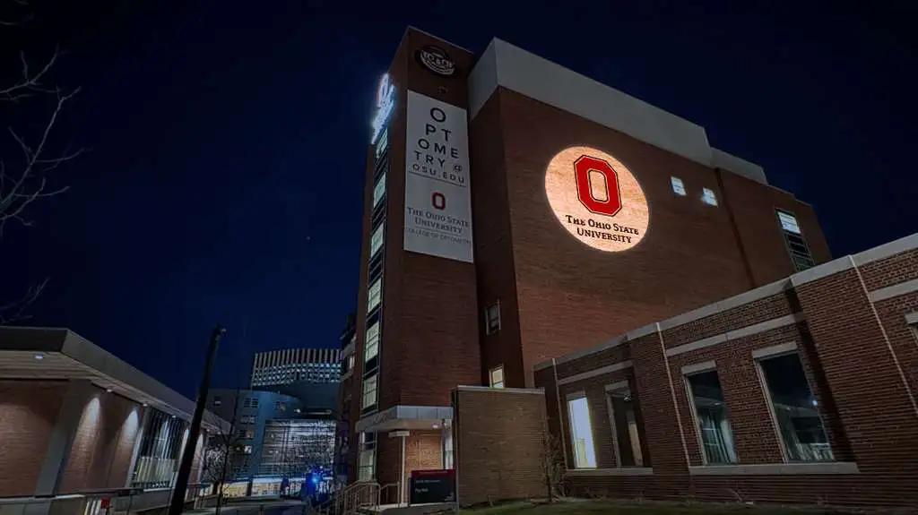 Ohio State University logo projected on a campus building tower at night