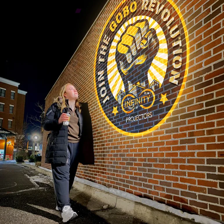JOIN THE GOBO REVOLUTION logo projected on a brick storefront wall along a sidewalk at night