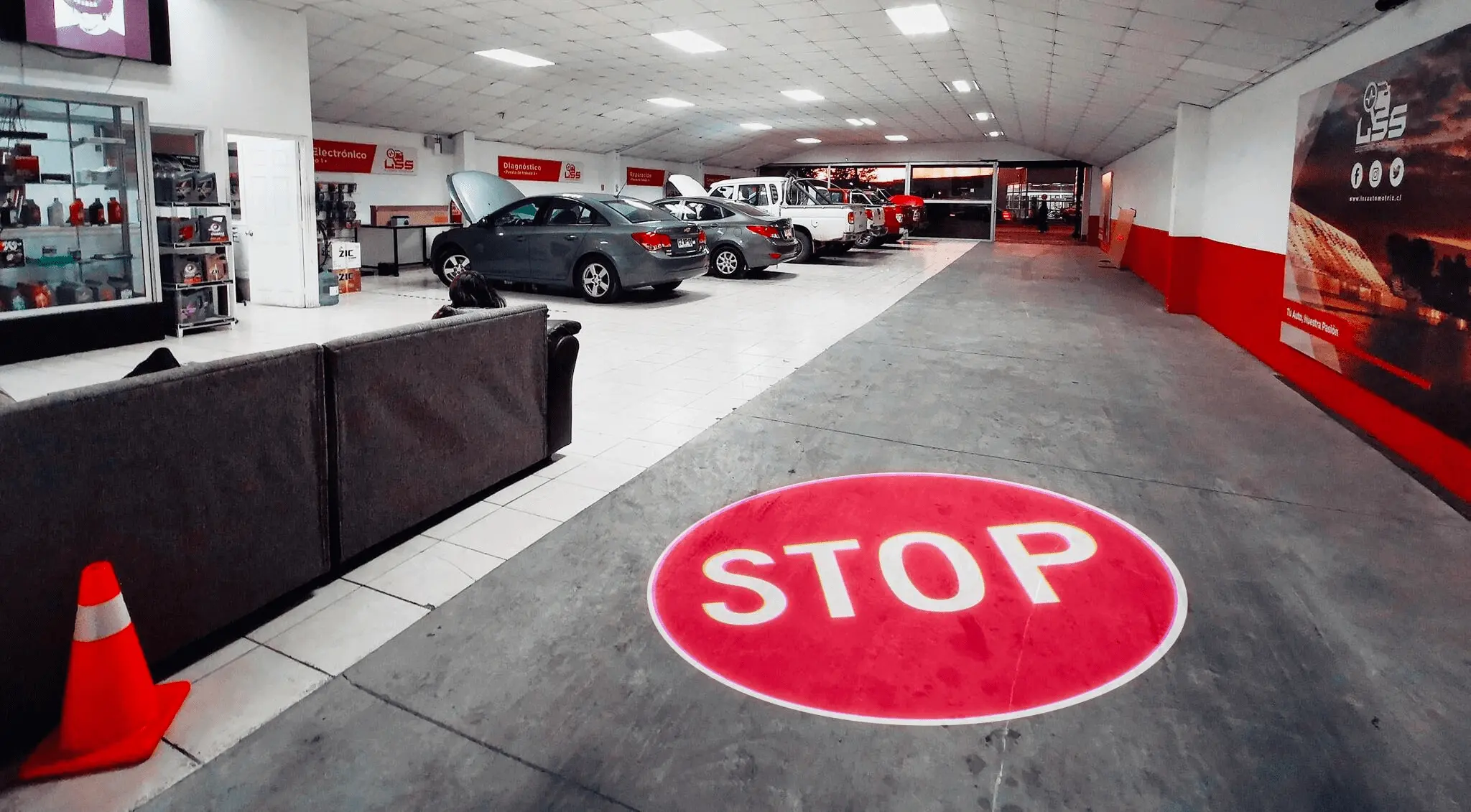 STOP sign projected on a parking-garage floor beside parked cars