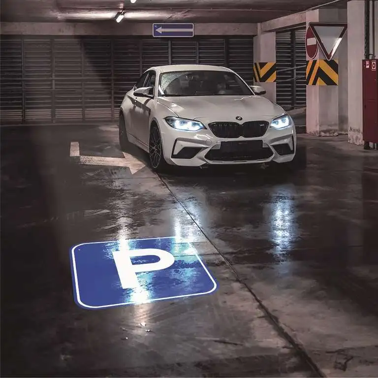 Parking symbol projected on a garage floor beside a parked car