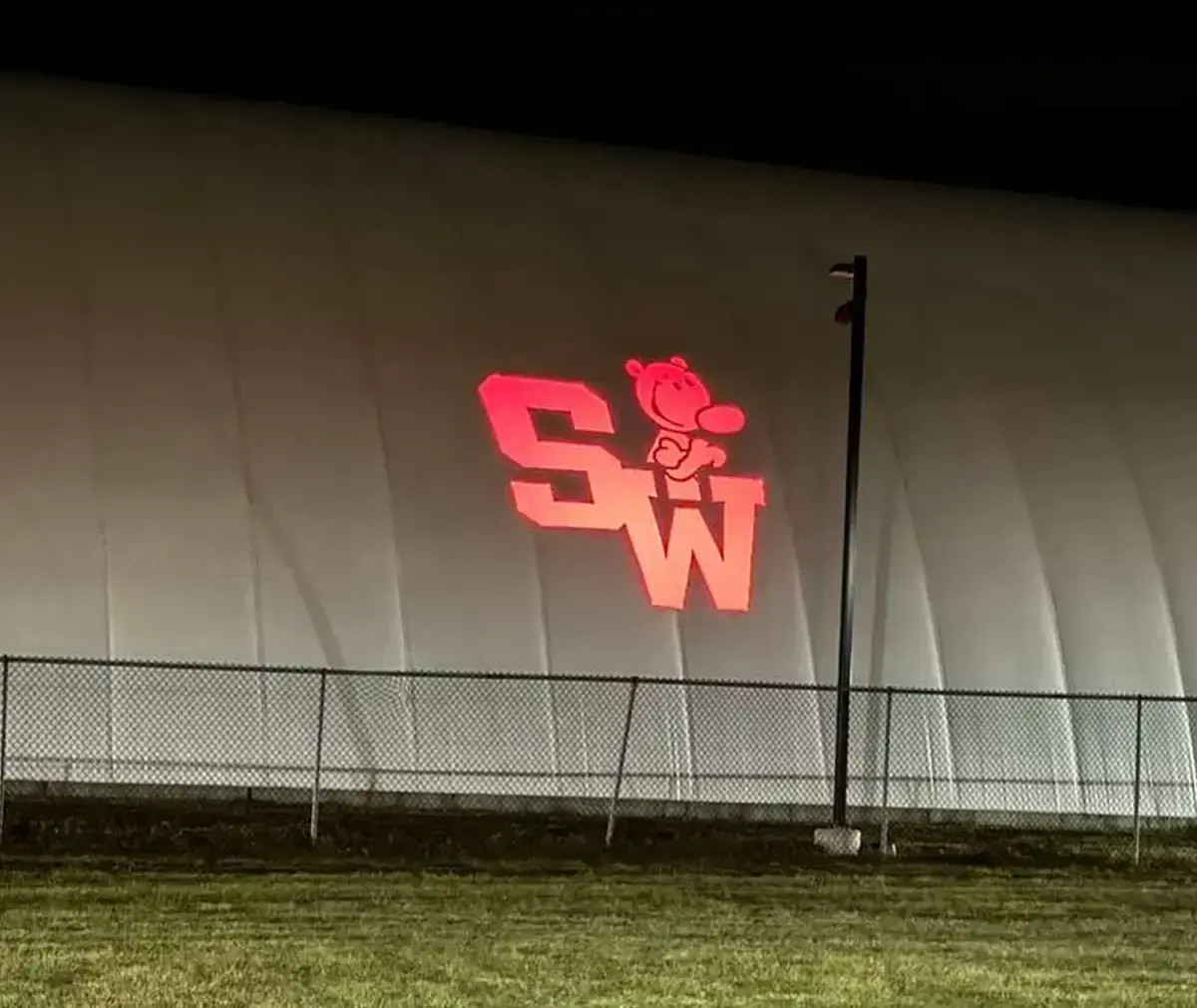 School mascot and initials projected at giant scale on an athletic sports dome