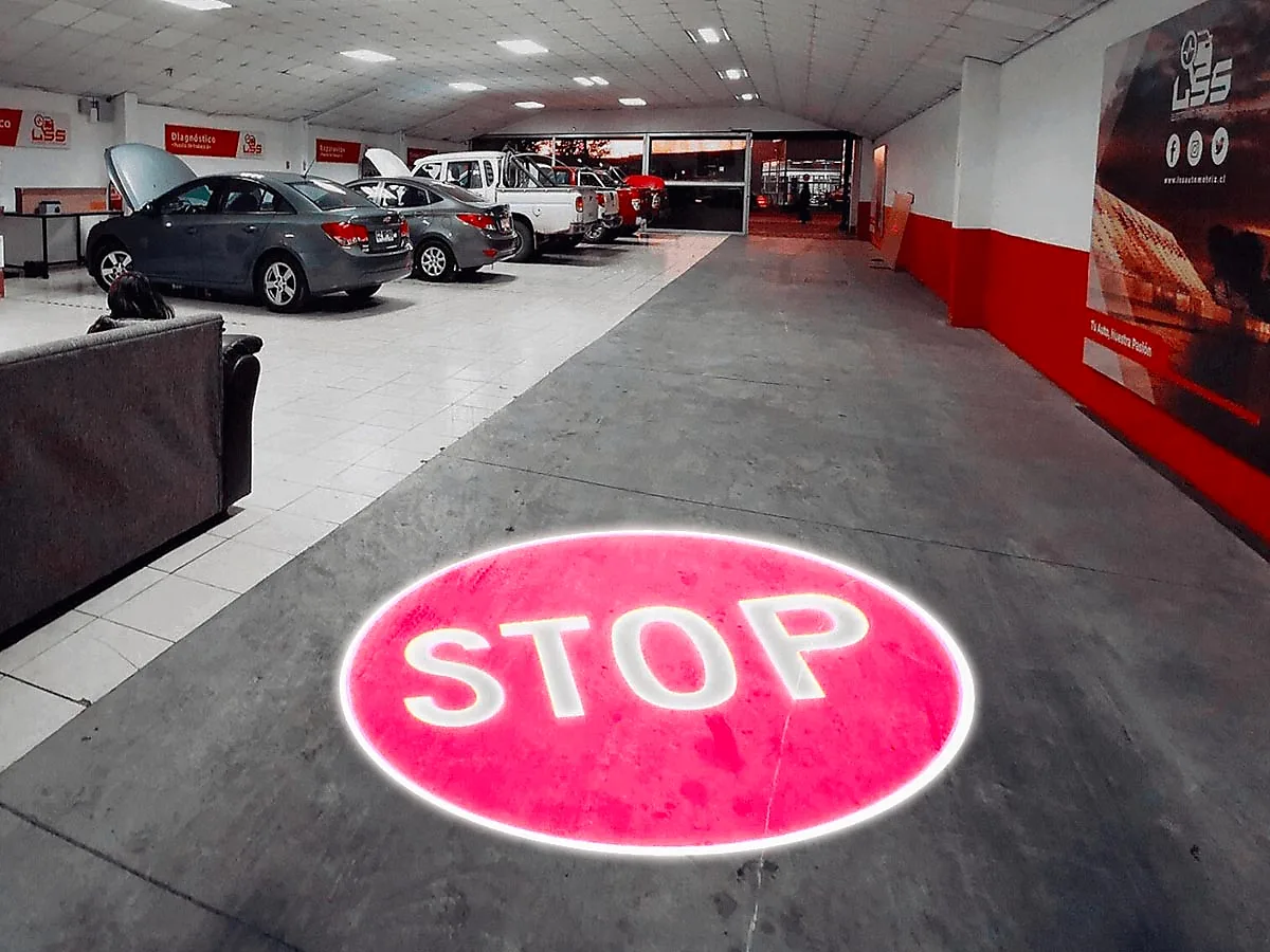 Bright red STOP sign projected on the floor of an auto service bay to warn drivers