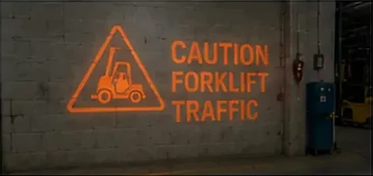 CAUTION FORKLIFT TRAFFIC sign projected on a warehouse wall beside a caution triangle — Infinity Projectors