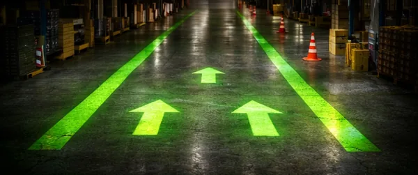 Green directional traffic arrows projected down a warehouse lane