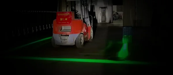 Forklift with a green projected safety boundary on the floor around it; the line turns red and a voice alarm sounds when a person approaches