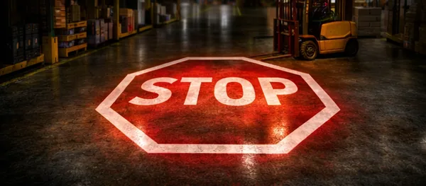 Bright red STOP sign projected onto a warehouse floor