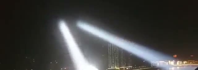 Twin searchlight beams crossing over a city skyline